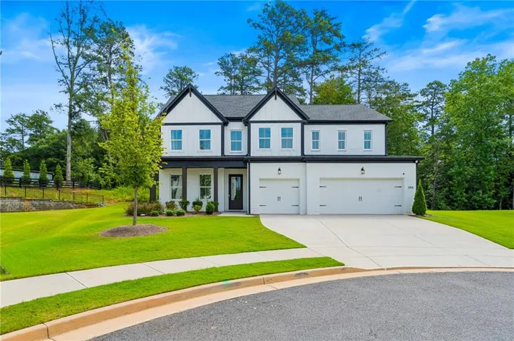 White exterior with black trim, a two-car garage, and a concrete driveway