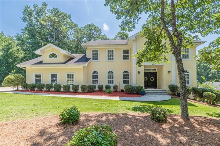 Stately two-story stucco exterior featuring multiple windows and a prominent dormer