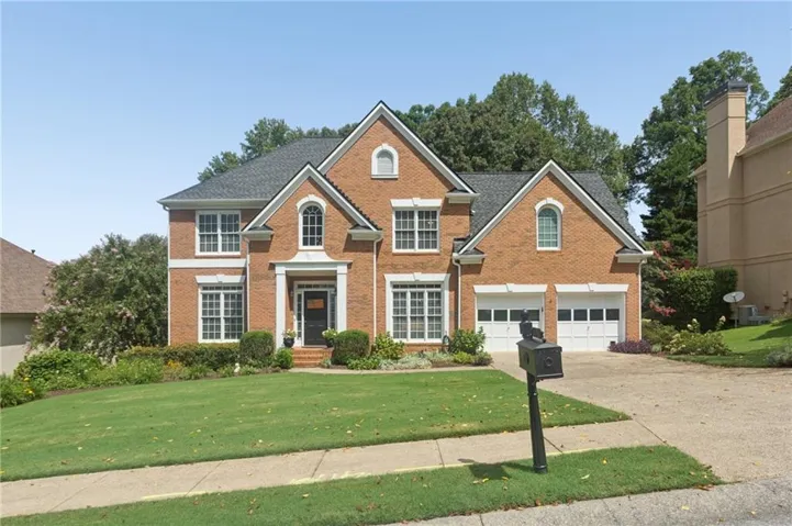 Brick exterior with white trim, arched windows, a covered entry, and an attached two-car garage