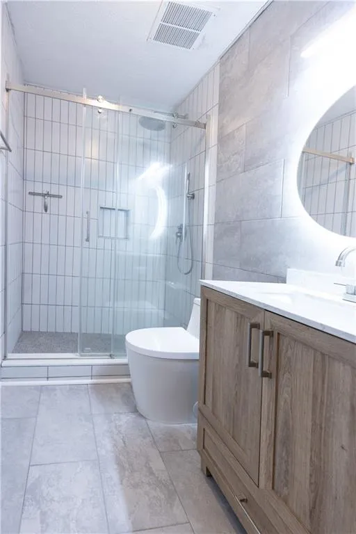 Contemporary bathroom featuring a frameless glass shower enclosure with vertical tile accents and a built-in niche