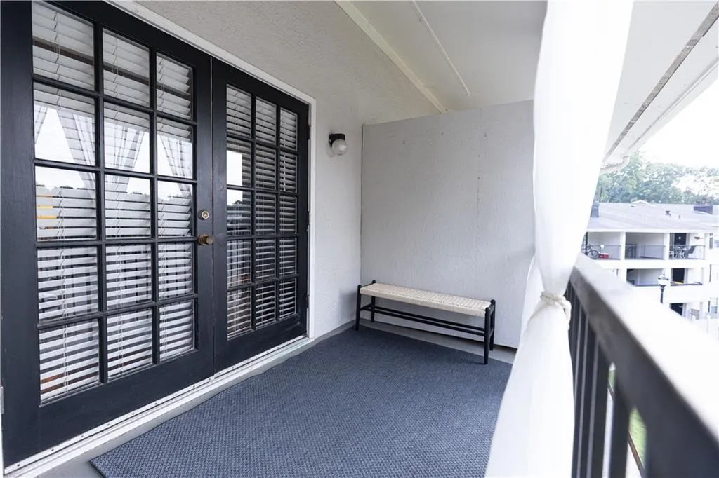 Balcony featuring double French doors with grid-patterned glass, integrated blinds, and a durable exterior surface