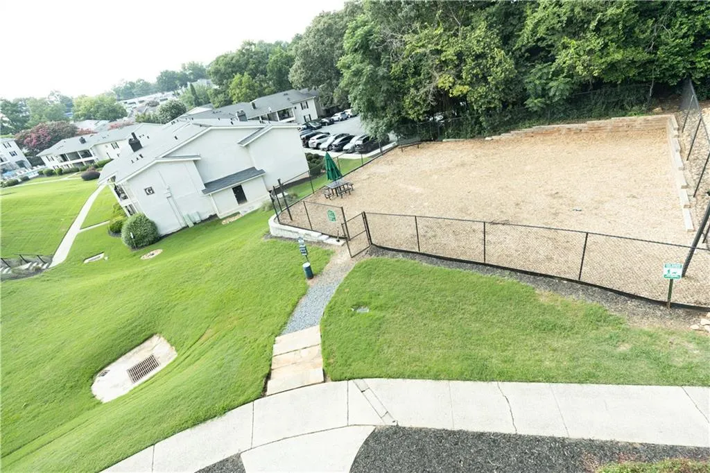 Fenced recreation area with a wood chip surface, surrounded by mature trees