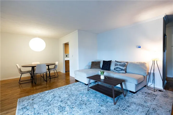 Open-concept living area featuring wood-finish flooring, white walls, and a built-in thermostat