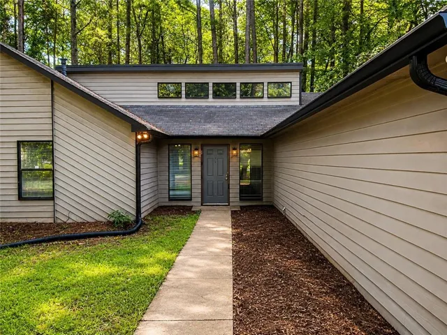 Contemporary exterior with beige siding, a dark gray front door, and transom windows