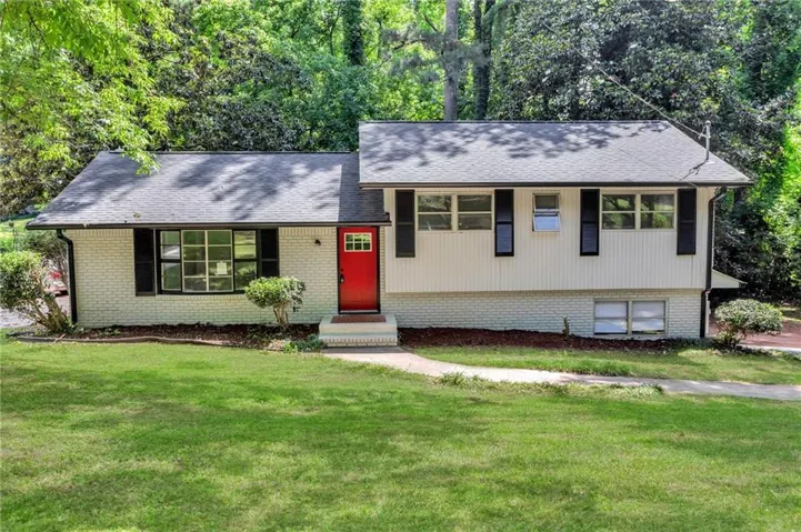 Split-level residence featuring a red entry door, white brick, and board and batten siding