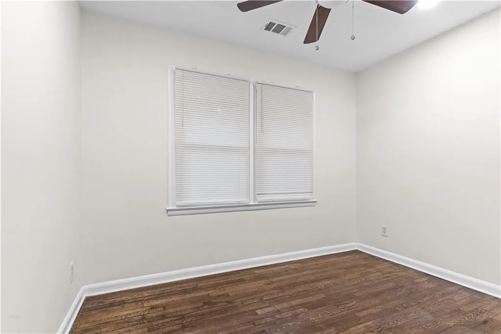 Empty room with dark wood finished floors and ceiling fan