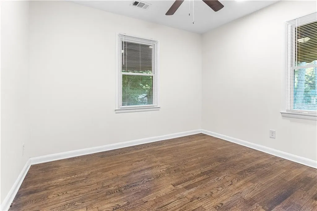 Empty room with dark wood-style flooring and ceiling fan