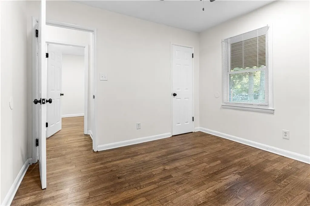 Unfurnished bedroom featuring dark wood-style flooring and ceiling fan