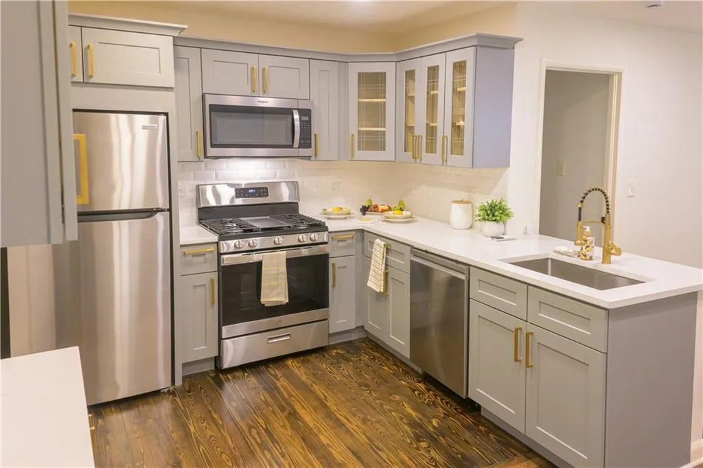 Kitchen featuring stainless steel appliances, tasteful backsplash, gray cabinets, and dark wood-style floors