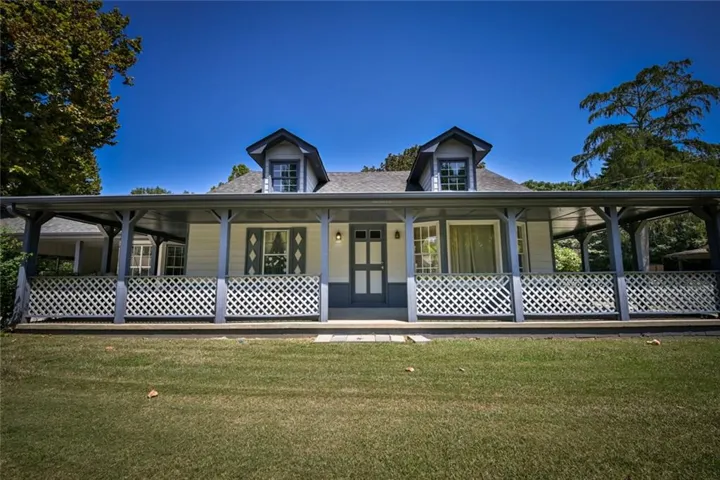 Gabled dormers, an expansive covered porch, decorative lattice railing, window shutters, and a central entry door