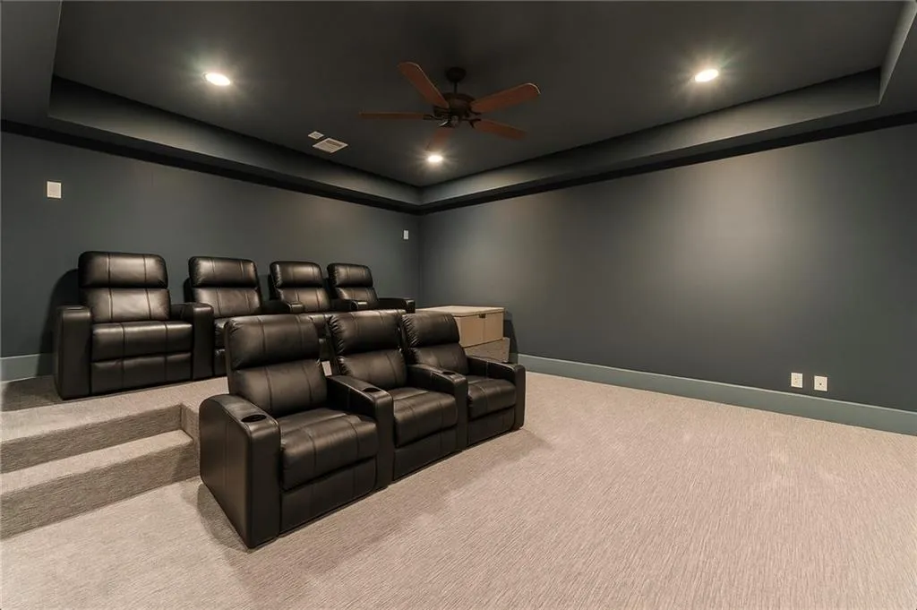 Home theater room with a raised ceiling, carpet floors, ceiling fan, and recessed lighting