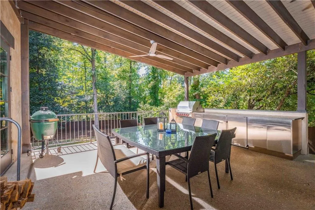 View of patio with area for grilling, outdoor dining space, and view of wooded area