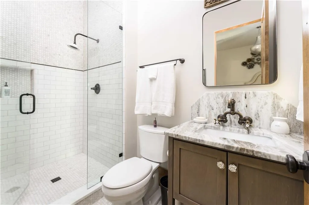 Full bath featuring vanity, a stall shower, and decorative backsplash