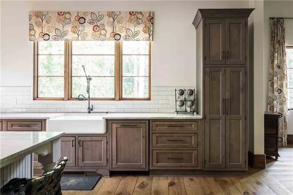 Kitchen featuring dark brown cabinets, light stone countertops, light wood-style flooring, and tasteful backsplash