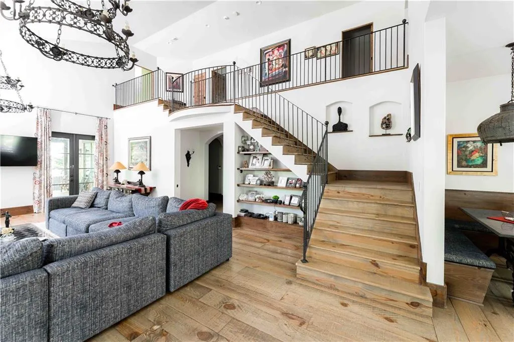 Living area with light wood-style floors, a high ceiling, stairway, french doors, and arched walkways