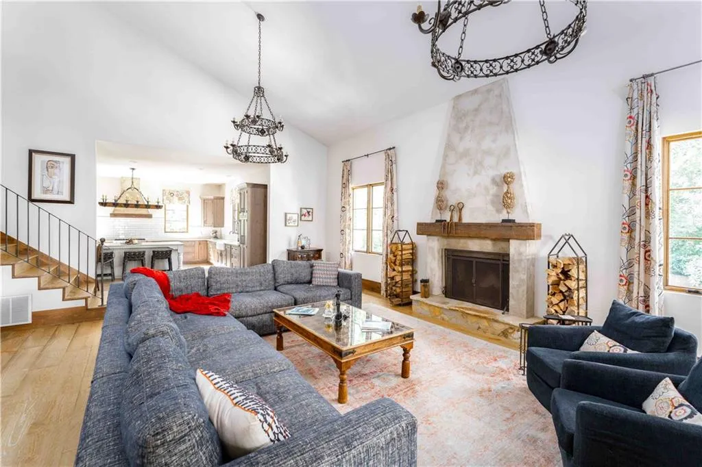 Living room featuring wood-type flooring, stairway, a fireplace, and high vaulted ceiling