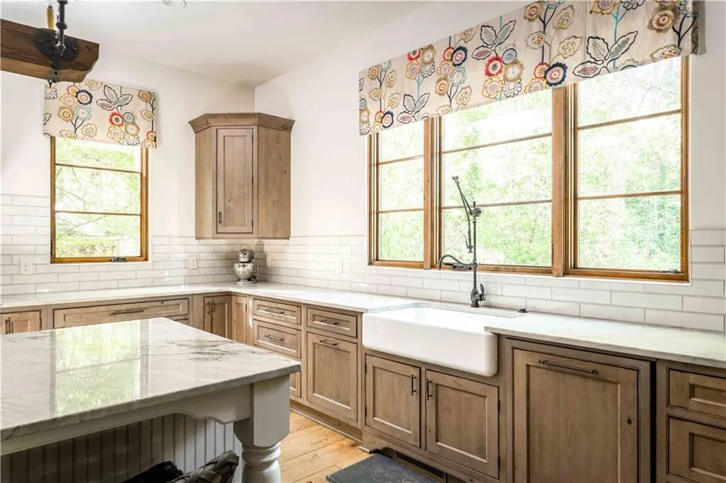Kitchen featuring tasteful backsplash, light stone counters, light wood-style floors, and brown cabinets