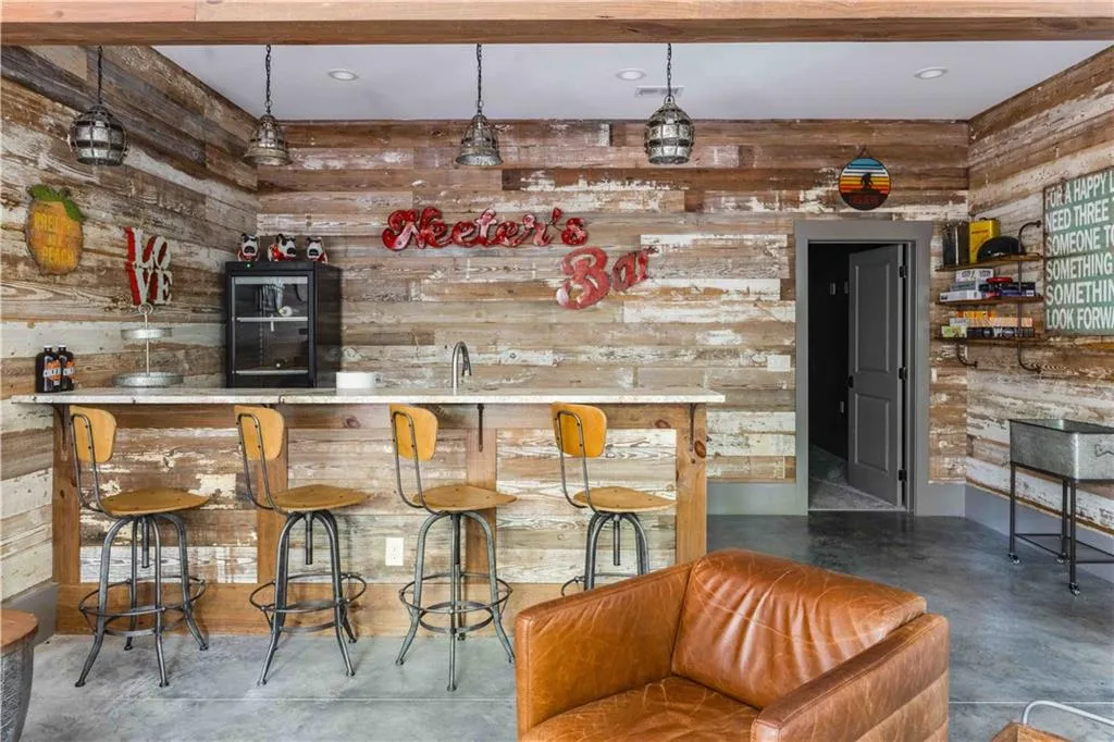 Indoor wet bar with finished concrete flooring, wood walls, and decorative light fixtures