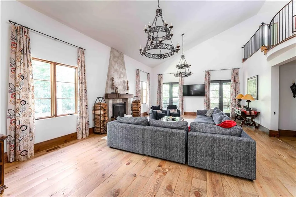 Living room with a large fireplace, light wood-style flooring, high vaulted ceiling, and a chandelier