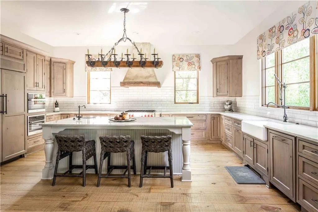 Kitchen featuring a breakfast bar area, a kitchen island with sink, decorative backsplash, and light wood-type flooring