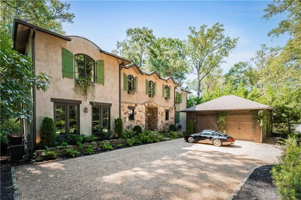 View of front of home featuring an outdoor structure, stucco siding, and gravel driveway