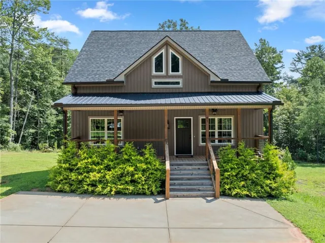 Board-and-batten siding with a covered front porch featuring wood posts and railings