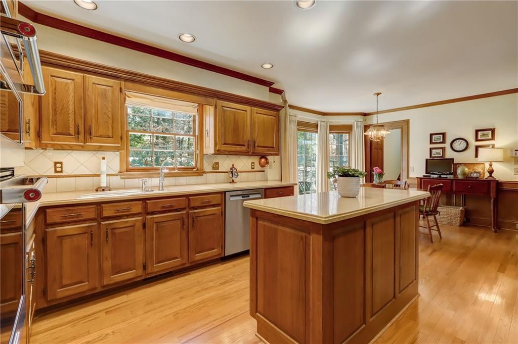 Dining space featuring light wood-type flooring, a notable chandelier, a healthy amount of sunlight, and ornamental molding