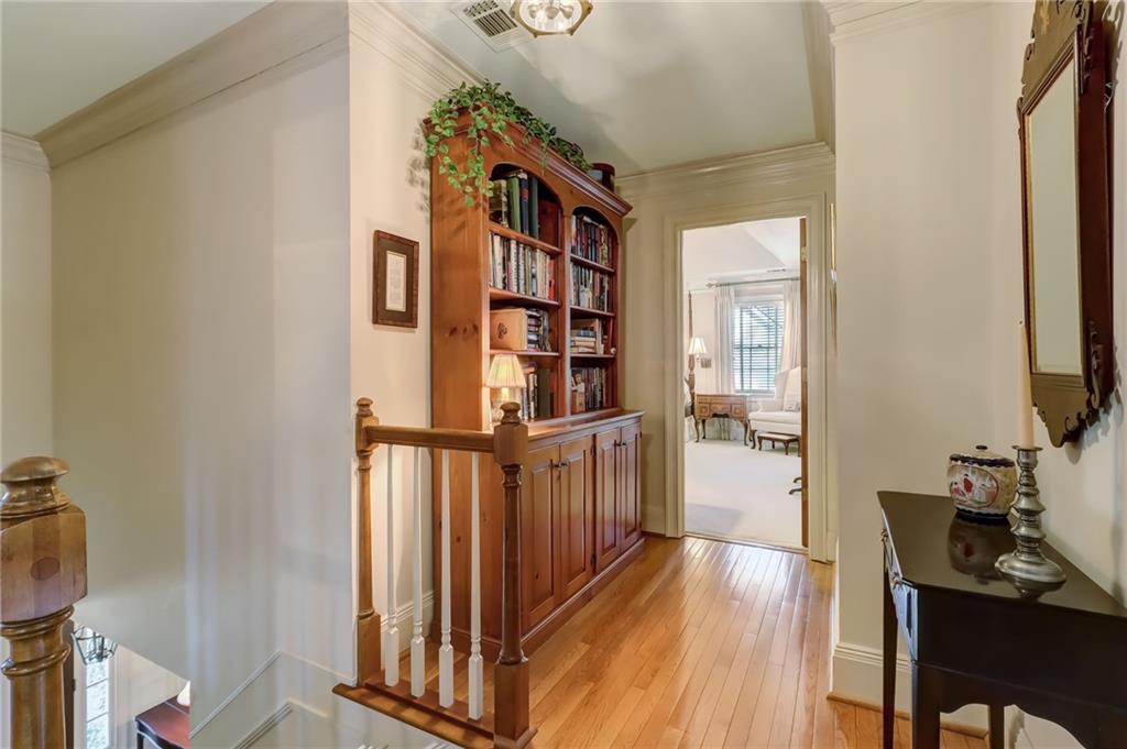 Upstairs Corridor with hardwood flooring and crown molding to the Primary Bedroom Suite
