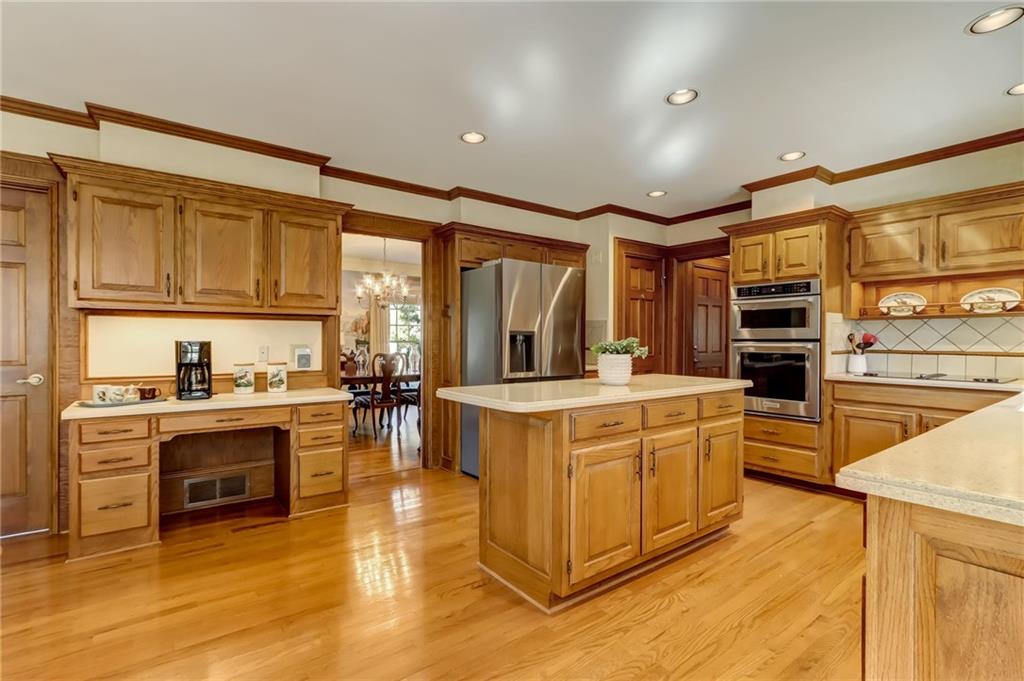 Kitchen with light hardwood / wood-style floors, ornamental molding, light stone countertops, tasteful backsplash, and stainless steel appliances