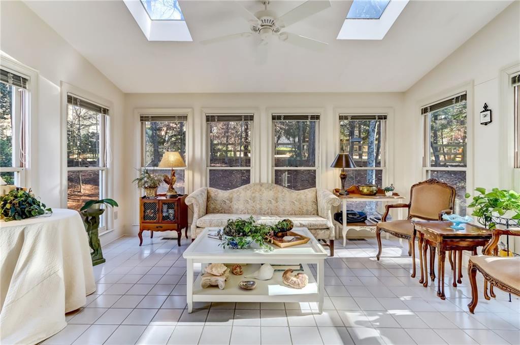 Sunroom / solarium featuring a healthy amount of sunlight, ceiling fan, and lofted ceiling with skylight