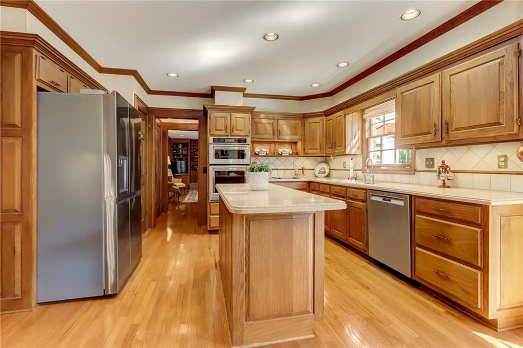 Kitchen with pendant lighting, light wood-type flooring, an inviting chandelier, tasteful backsplash, and dishwasher