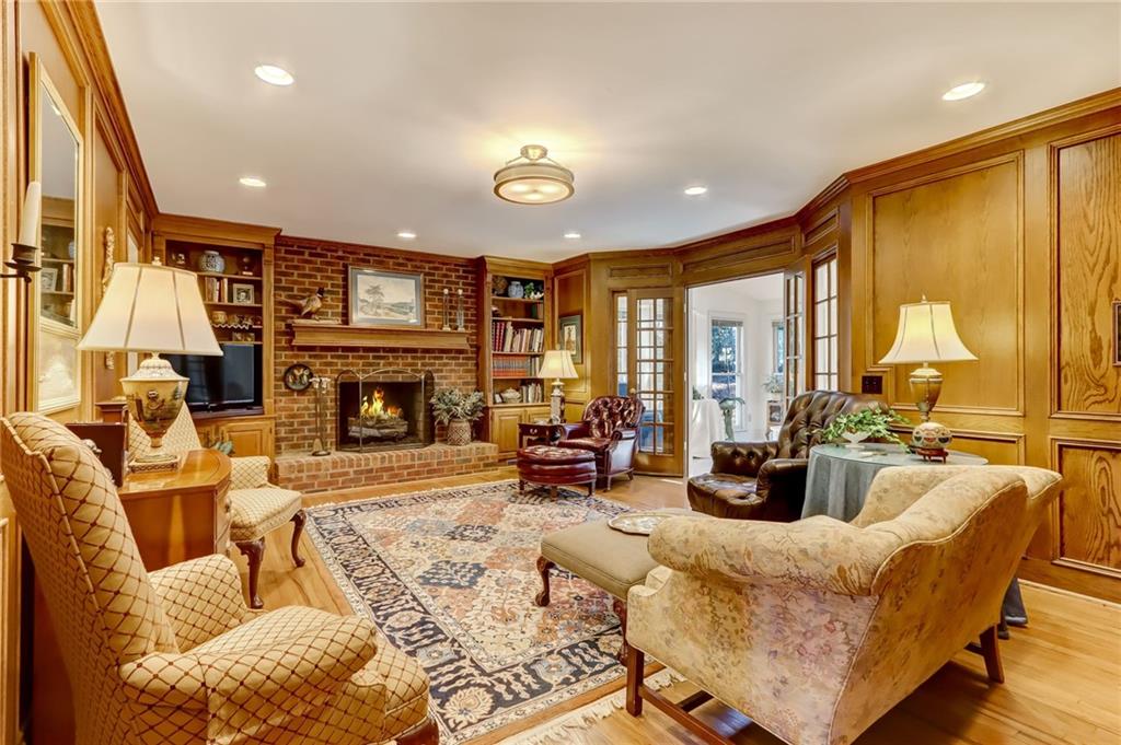 Living room with a fireplace, light hardwood / wood-style floors, brick wall, and french doors