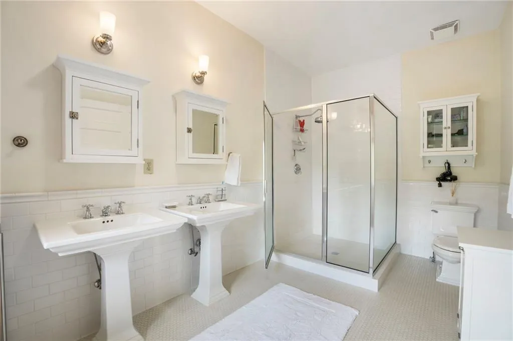 Full bathroom with tile walls, a wainscoted wall, a shower stall, and tile patterned flooring