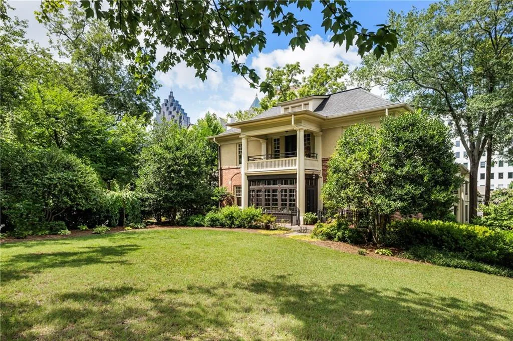 Rear view of property with a balcony, a lawn, brick siding, and stucco siding