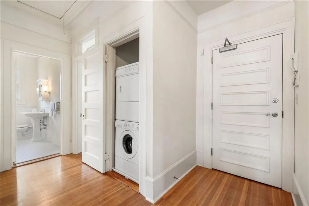 Laundry room featuring estacked washer and dryer, wood finished floors, and attic access