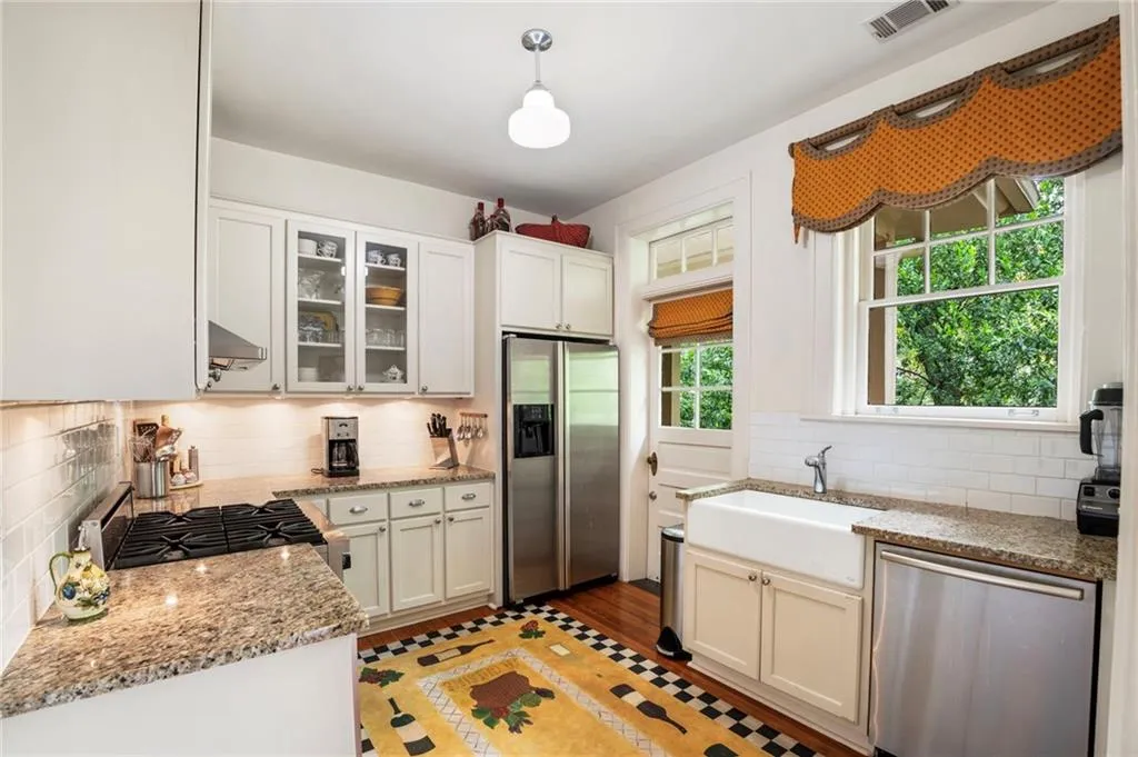 Kitchen featuring appliances with stainless steel finishes, decorative backsplash, light stone countertops, and glass insert cabinets