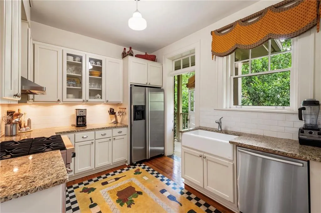 Kitchen featuring stainless steel appliances, tasteful backsplash, white cabinets, and light stone countertops