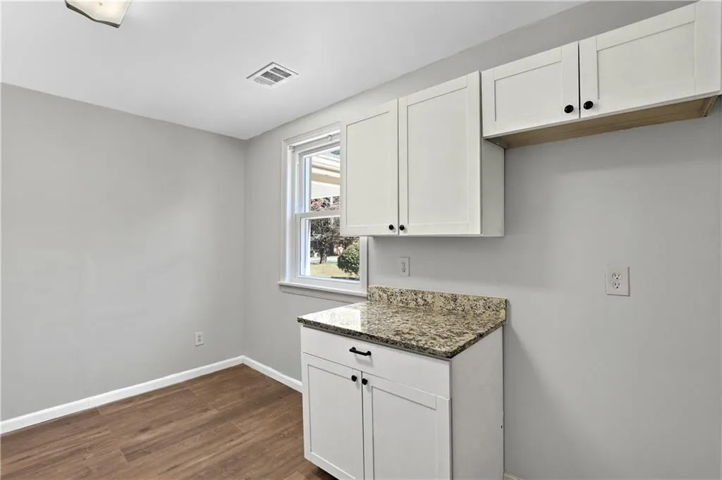 Kitchen featuring white cabinets, dark stone counters, and dark wood-style flooring