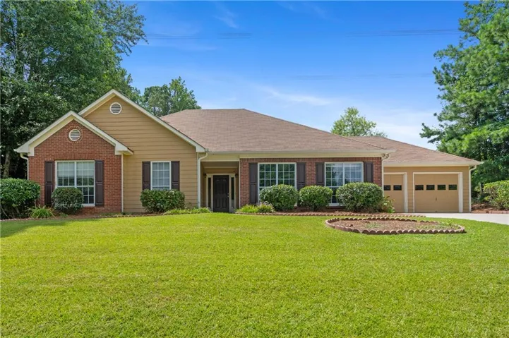 A front view highlights the home’s single-level design, brick accents, established lawn, and welcoming covered entrance.