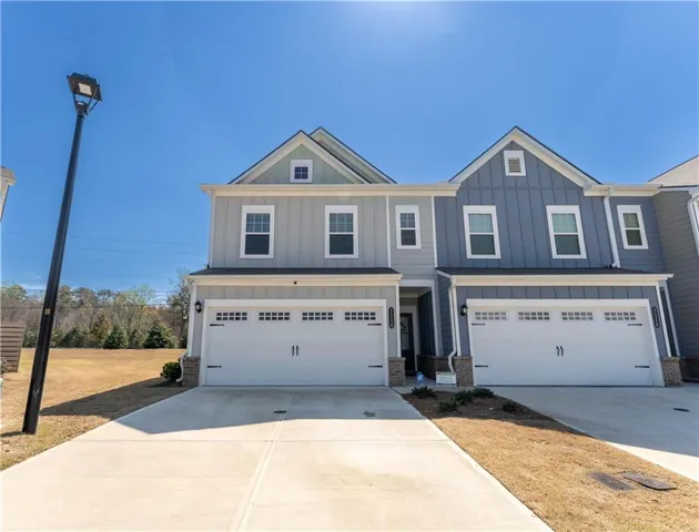 View of front of home featuring board and batten siding, an attached garage, concrete driveway, and brick siding