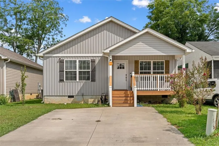 Light gray siding exterior with a covered front porch featuring white railings and wood-finish steps