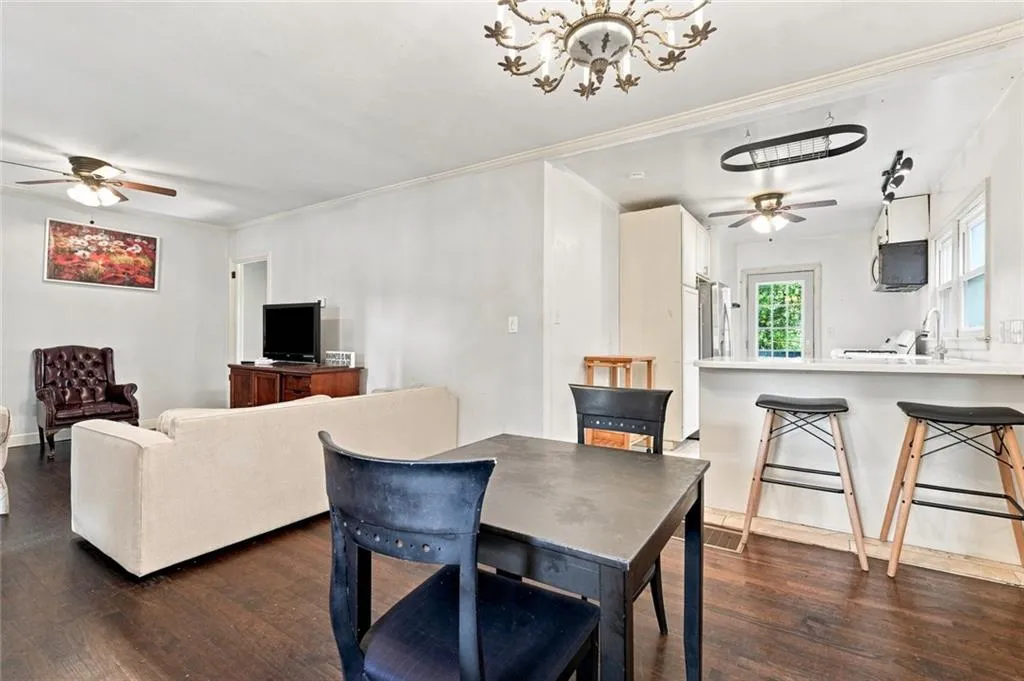 Open-concept living space featuring wood-finish flooring, a kitchen with a breakfast bar, white countertops, white cabinetry, and a ceiling fan