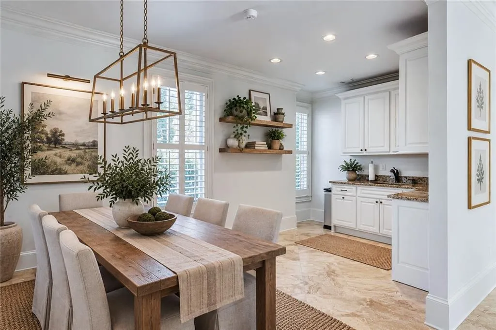 Spacious dining area with a rustic wood-finish table, a bronze-finish chandelier, and plantation shutters