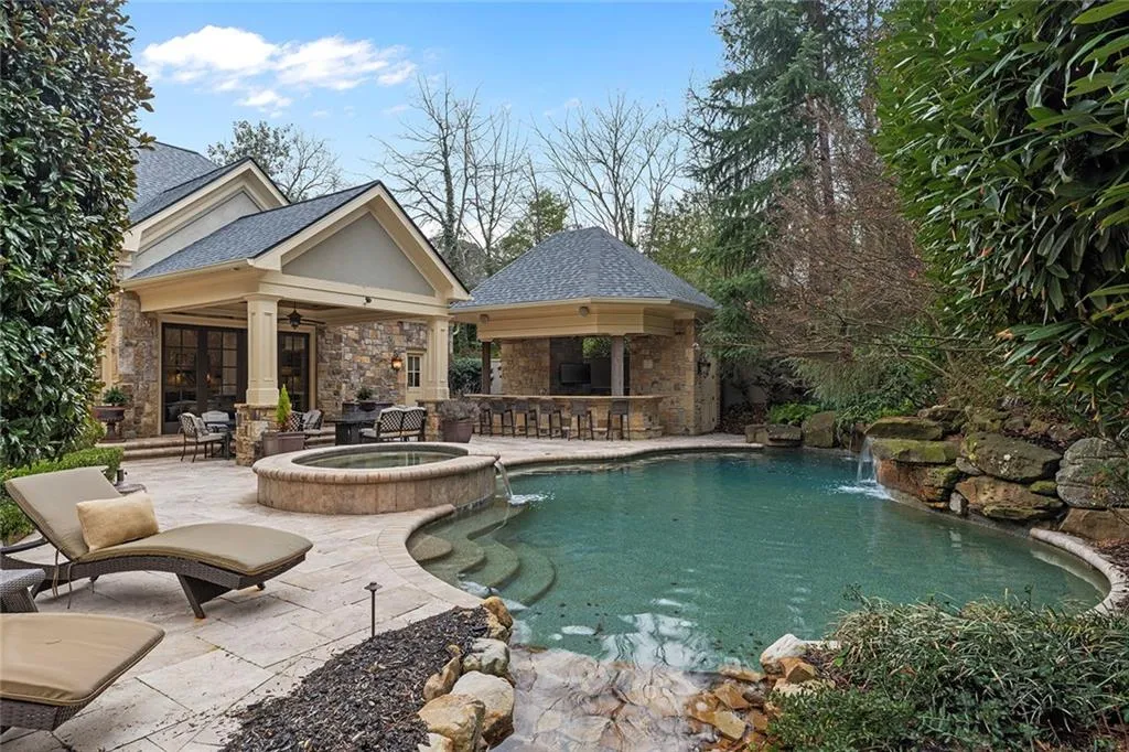 Integrated pool / hot tub featuring a bar, a patio, an exterior structure, and an outdoor structure