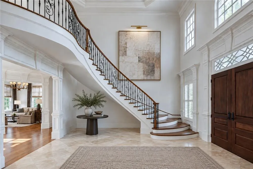 Grand foyer featuring a curved staircase with wrought iron balusters and wood-finish handrails