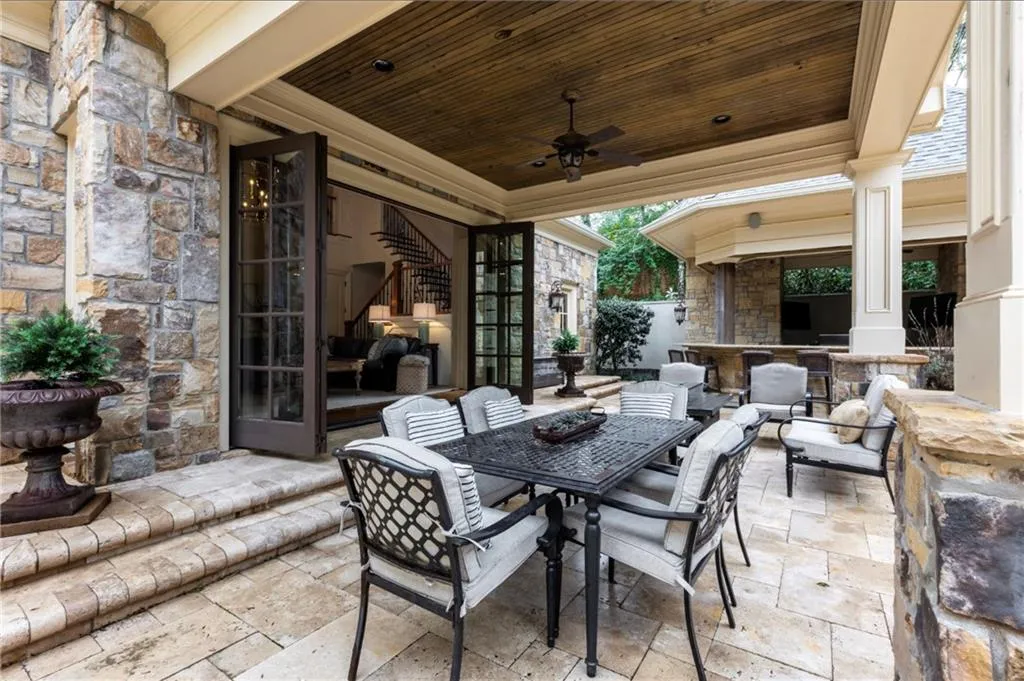 Stone exterior with a covered patio featuring a wood-panel ceiling, ceiling fan, and recessed lighting