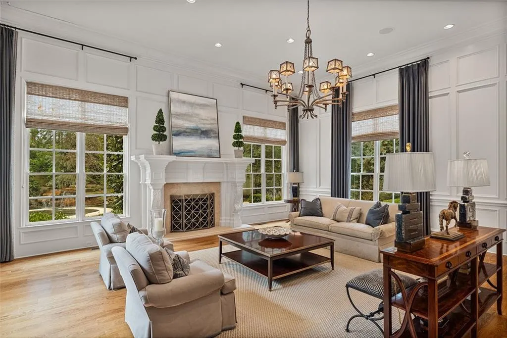 Living room with a decorative wall, crown molding, light wood-style flooring, a fireplace, and hanging lights