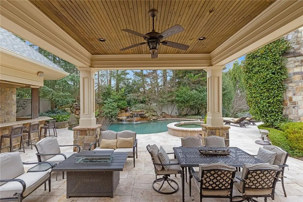 Fenced backyard with an outdoor bar and dining area, ceiling fan, a patio area, and a fire pit