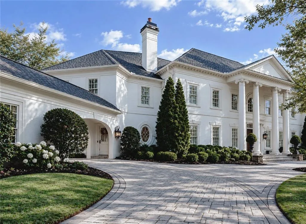 Stately white exterior with a columned portico, multi-pane windows, and a paved circular driveway