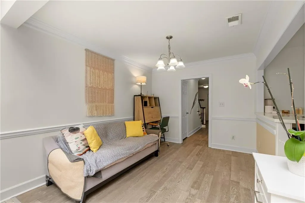 Living room featuring ornamental molding, light wood-type flooring, and a chandelier